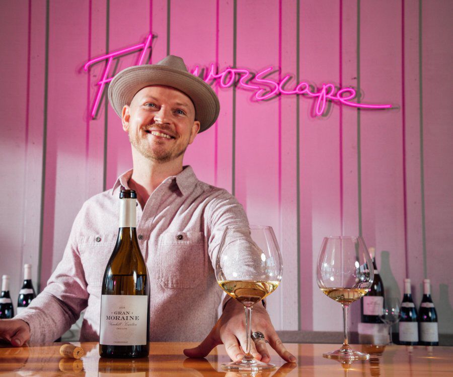 Gran Moraine Winemaker Shane Moore with glass of wine and a bottle of Gran Moraine