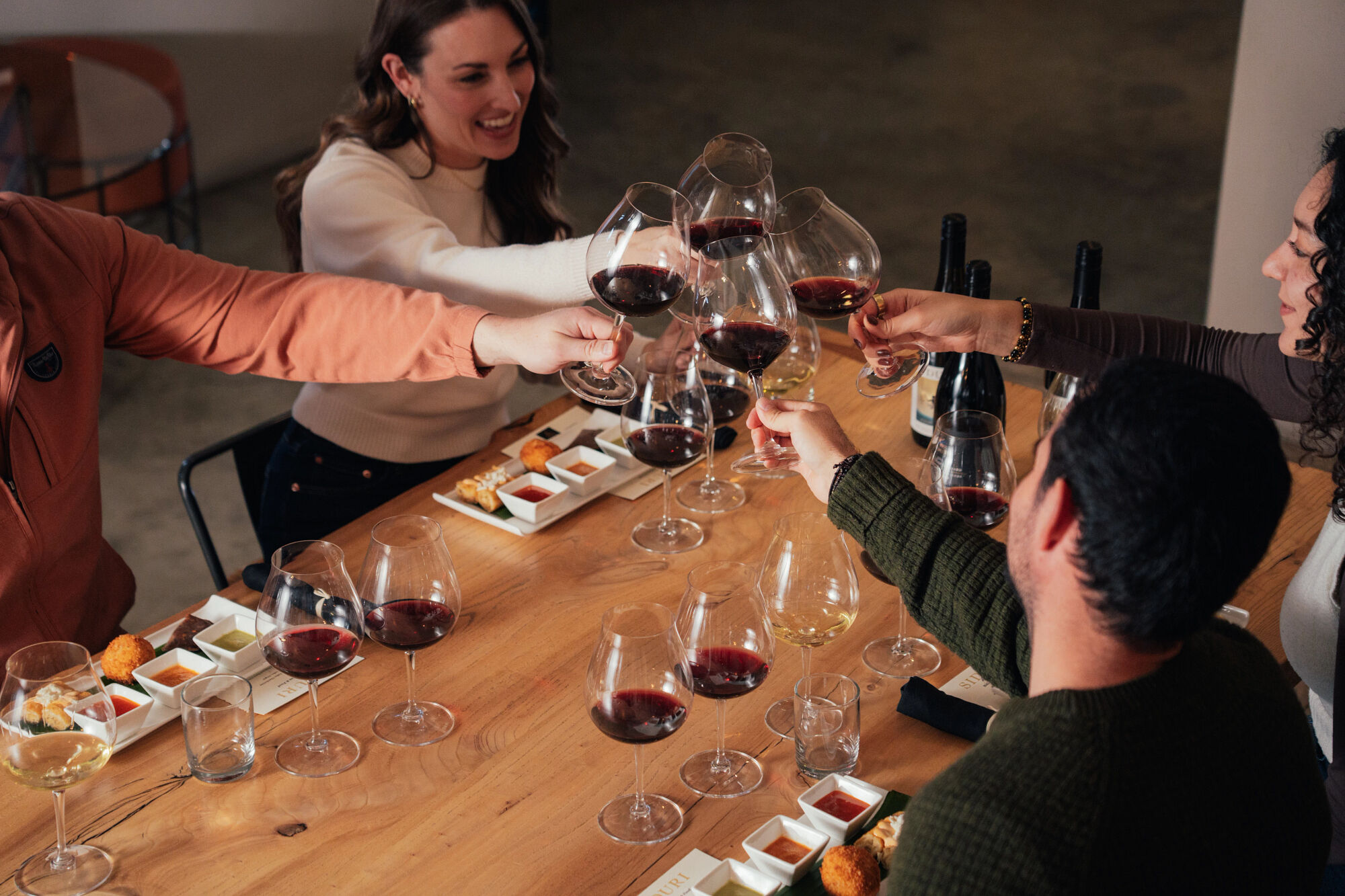 A group of friends toasting to a tasting at Siduri