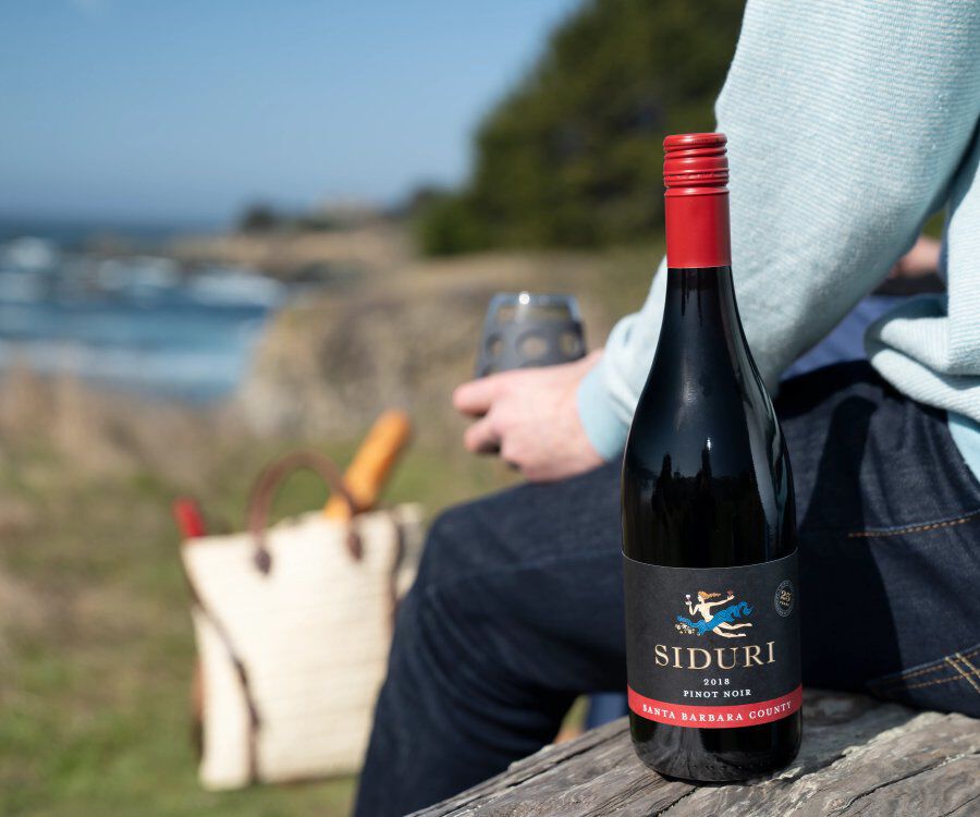 Siduri Pinot Bottle sitting next to a person