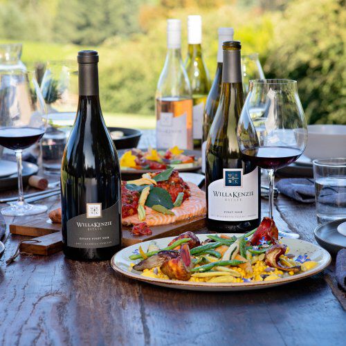 WillaKenzie wines on table with food and glasses of wine.